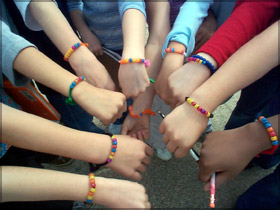 Student hands wearing solar beads.