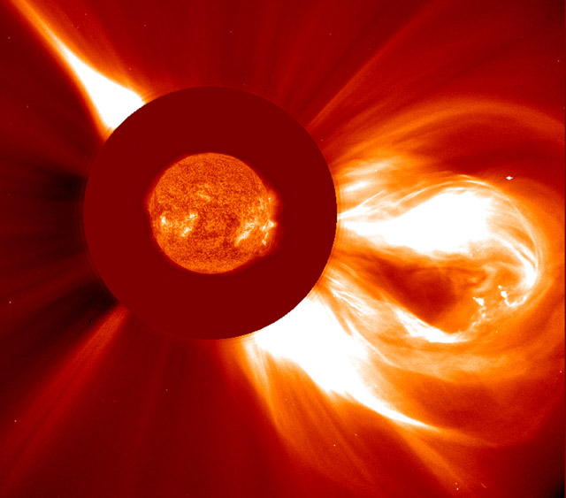 CME blast -- A large coronal mass ejection ejects a cloud of particles into space on 2 December 2003. In this composite an EIT 304 image of the sun from about the same time has been appropriately scaled and superimposed on a LASCO C2 image where a red occulting disk can be seen extending around the Sun. This LASCO coronagraph instrument allows details in the corona to be observed. 